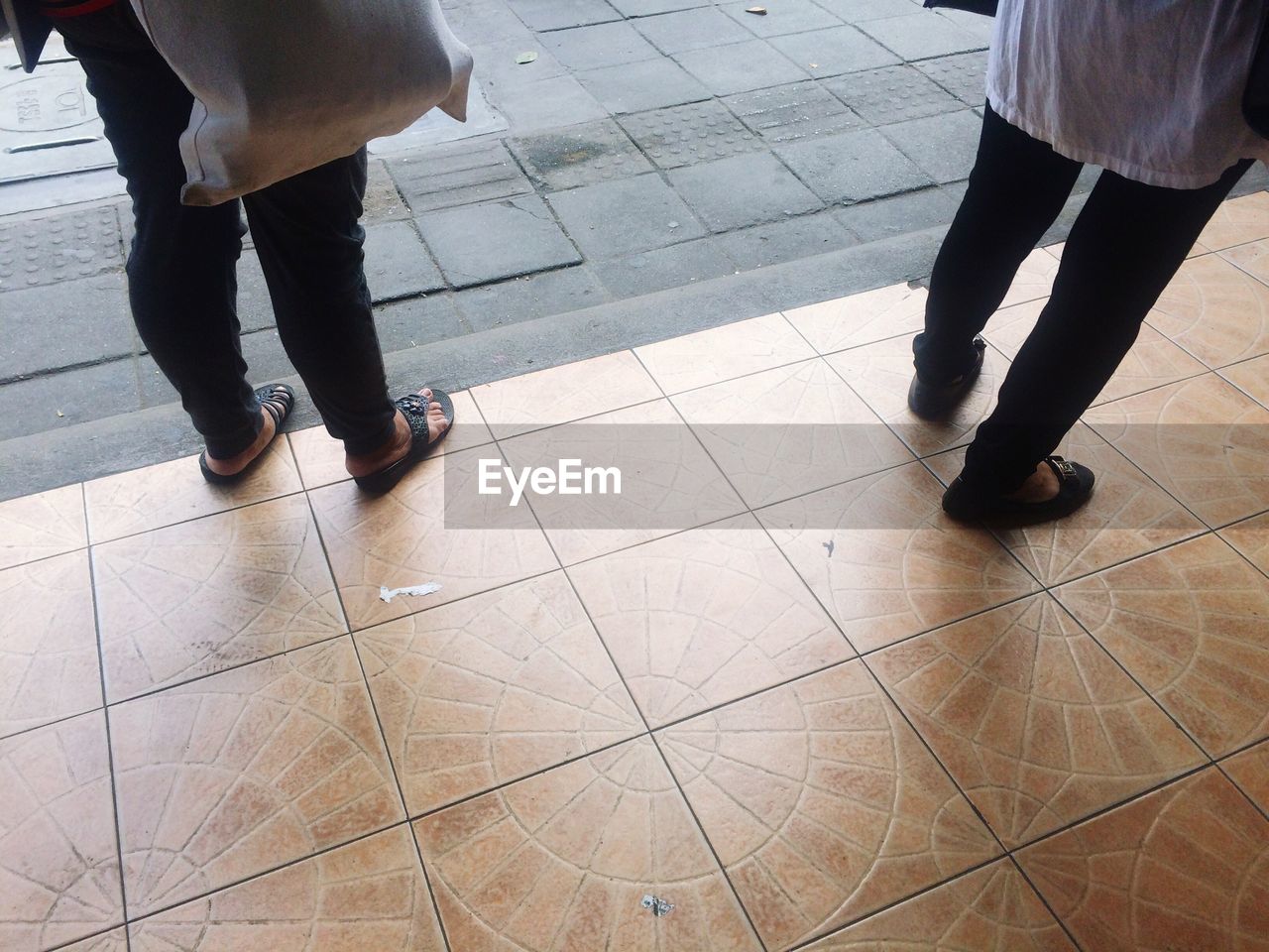 LOW SECTION OF PEOPLE WALKING ON TILED FLOOR