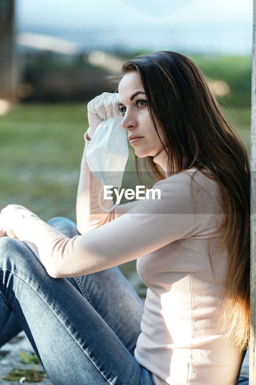 side view of young woman sitting on bench