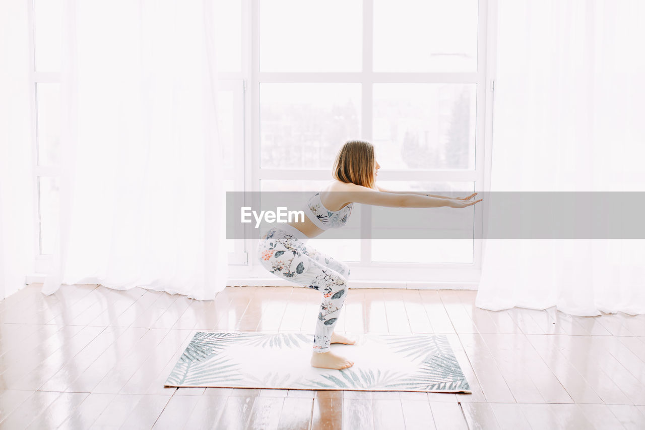 Girl in a sports uniform does exercises, physical exercises, yoga and stretches at home