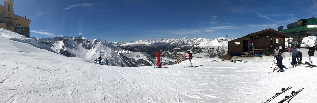 PEOPLE WALKING ON SNOWCAPPED MOUNTAINS AGAINST SKY