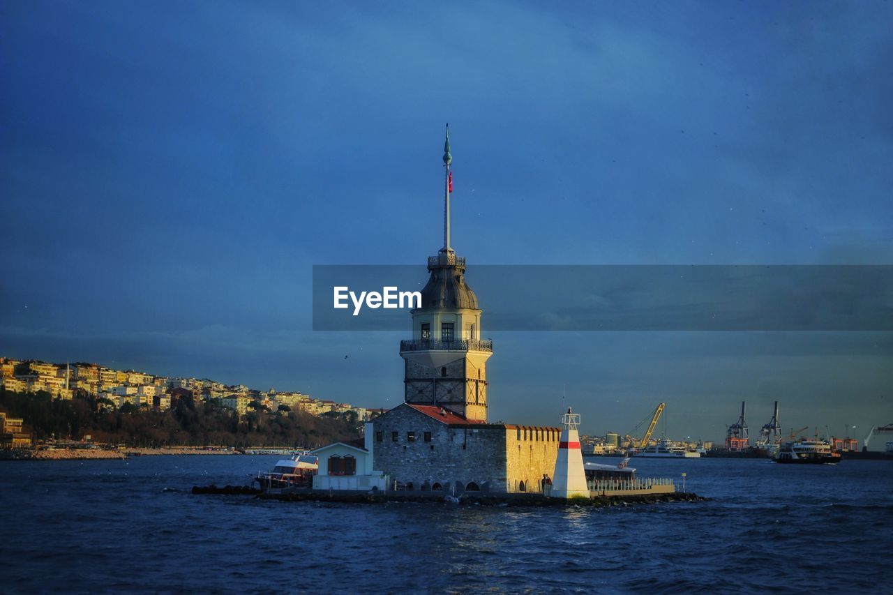 Sailboat on sea by buildings against sky