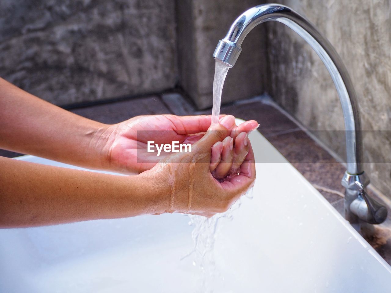 Cropped hand of woman washing hands in bathroom