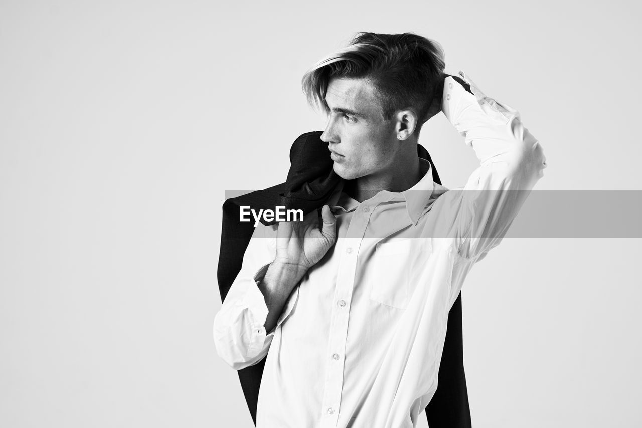 Young man looking away against white background