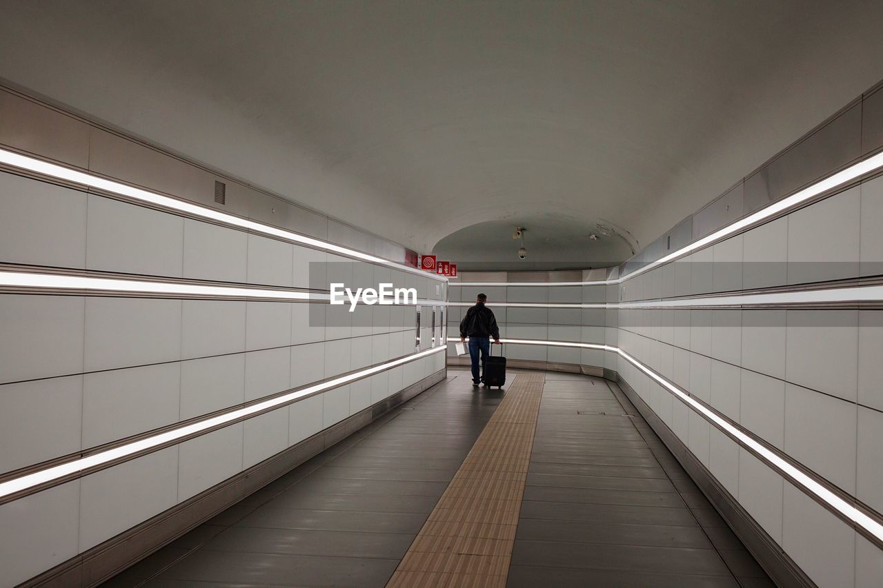 Rear view of people walking in illuminated tunnel