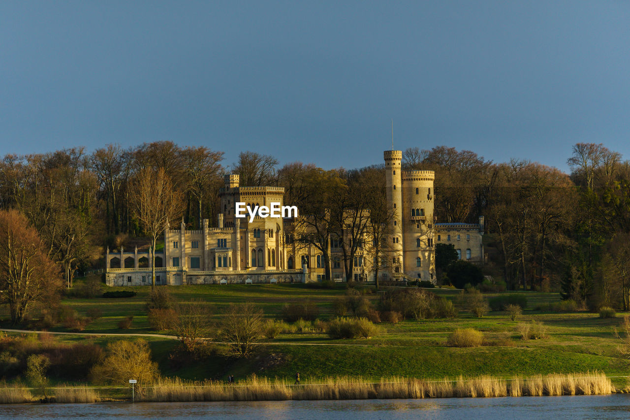 Building by lake against clear sky