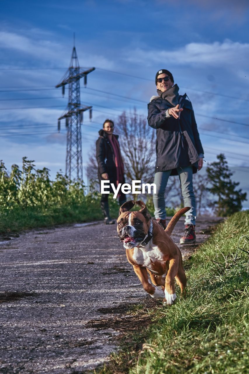 PEOPLE WITH DOG ON STREET AGAINST SKY