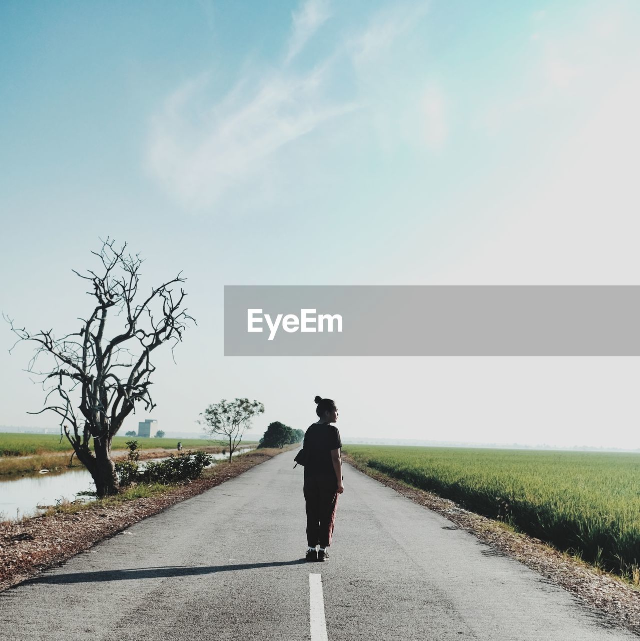 Rear view of woman standing on road against sky
