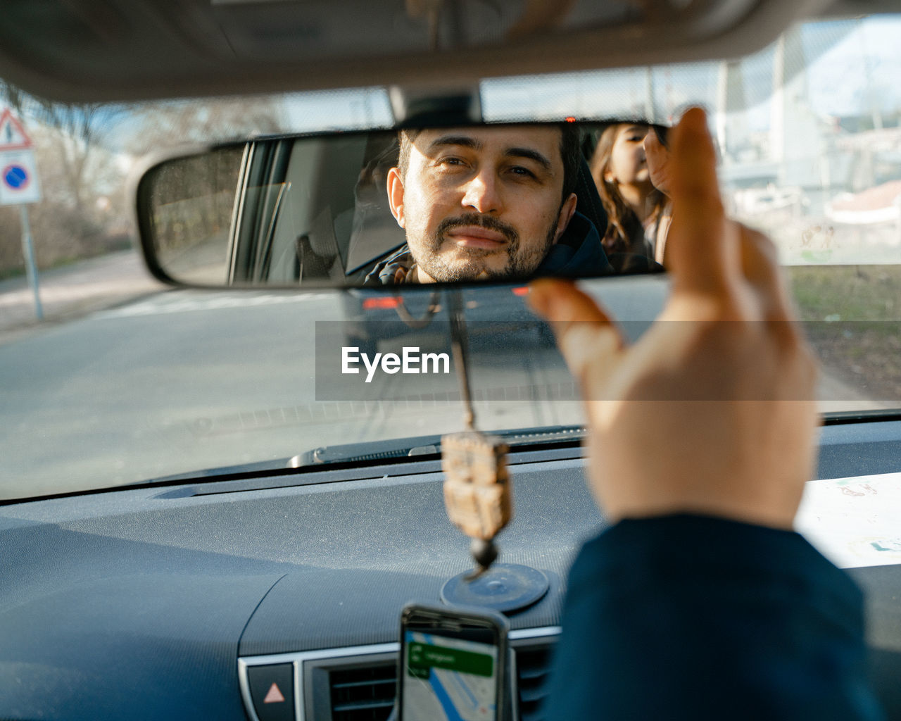 Man looking to daughter through car mirror 