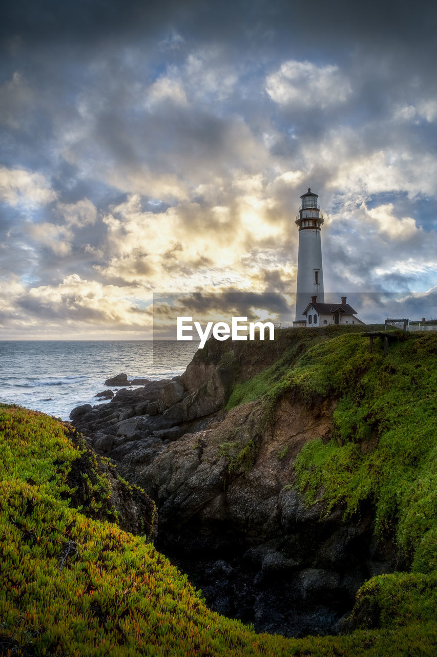 Lighthouse by sea against sky