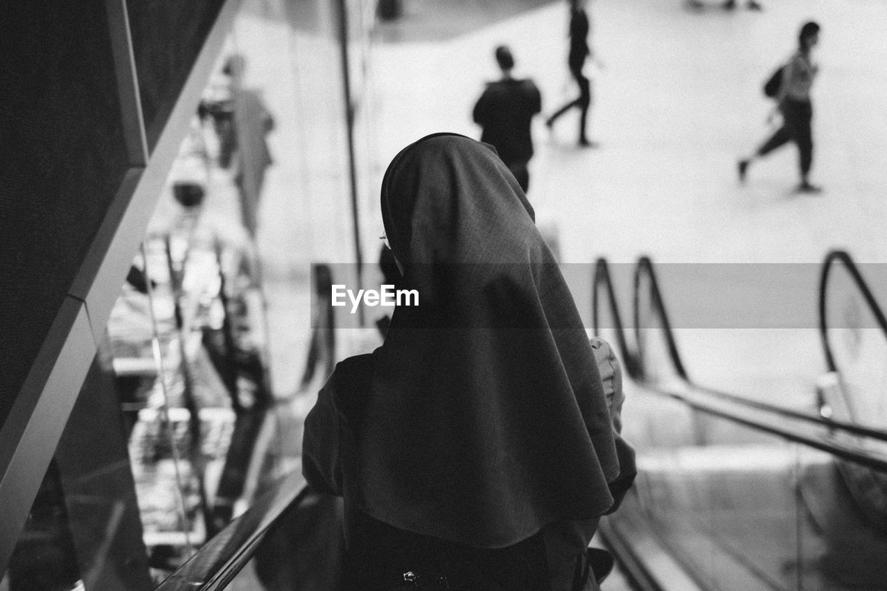 Rear view of a nun on escalator