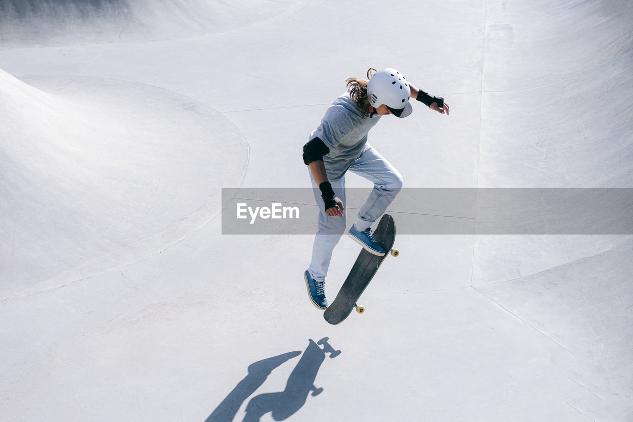 Skateboarder doing stunt with skateboard on sunny day