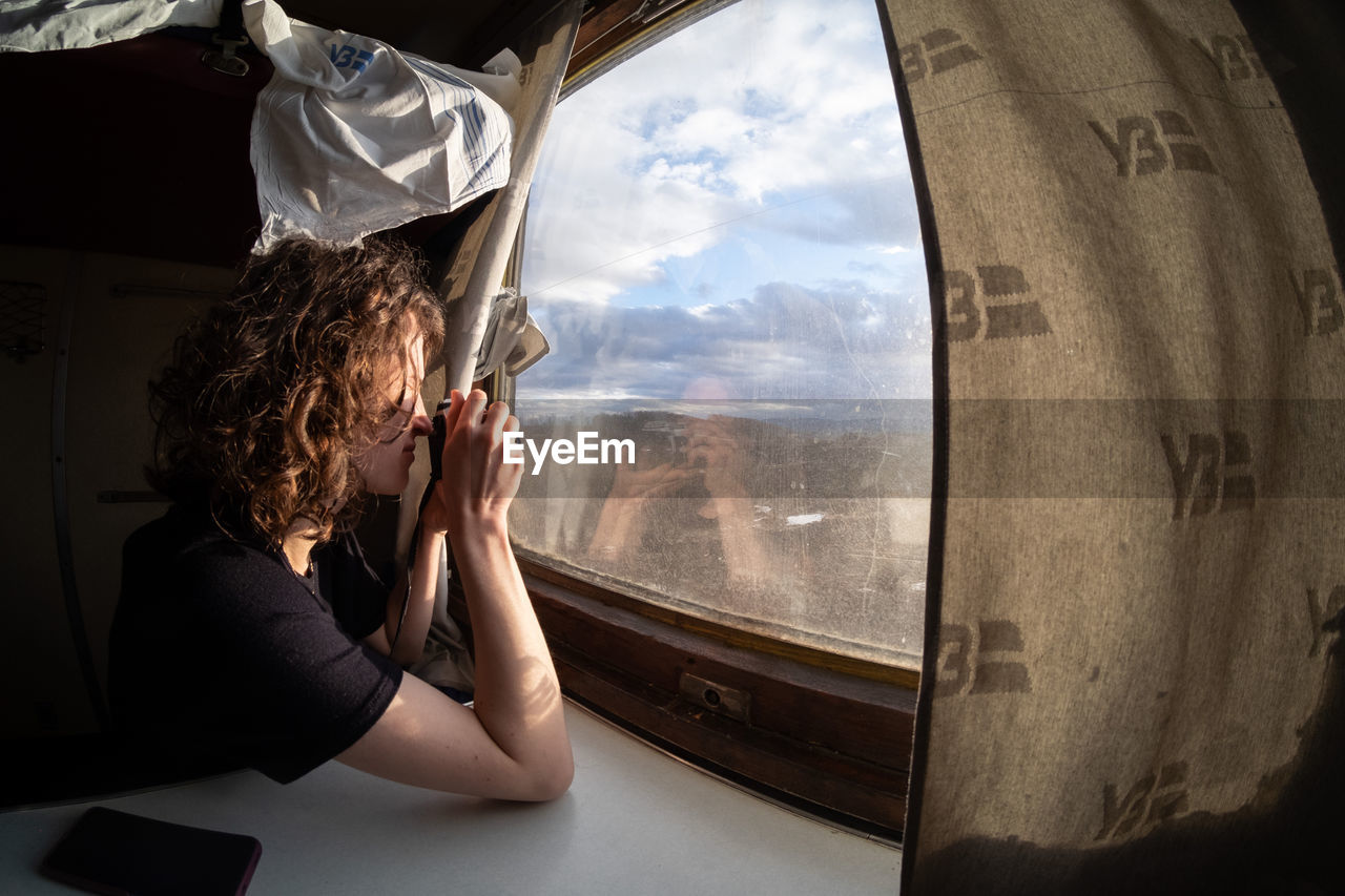 Rear view of woman looking through window