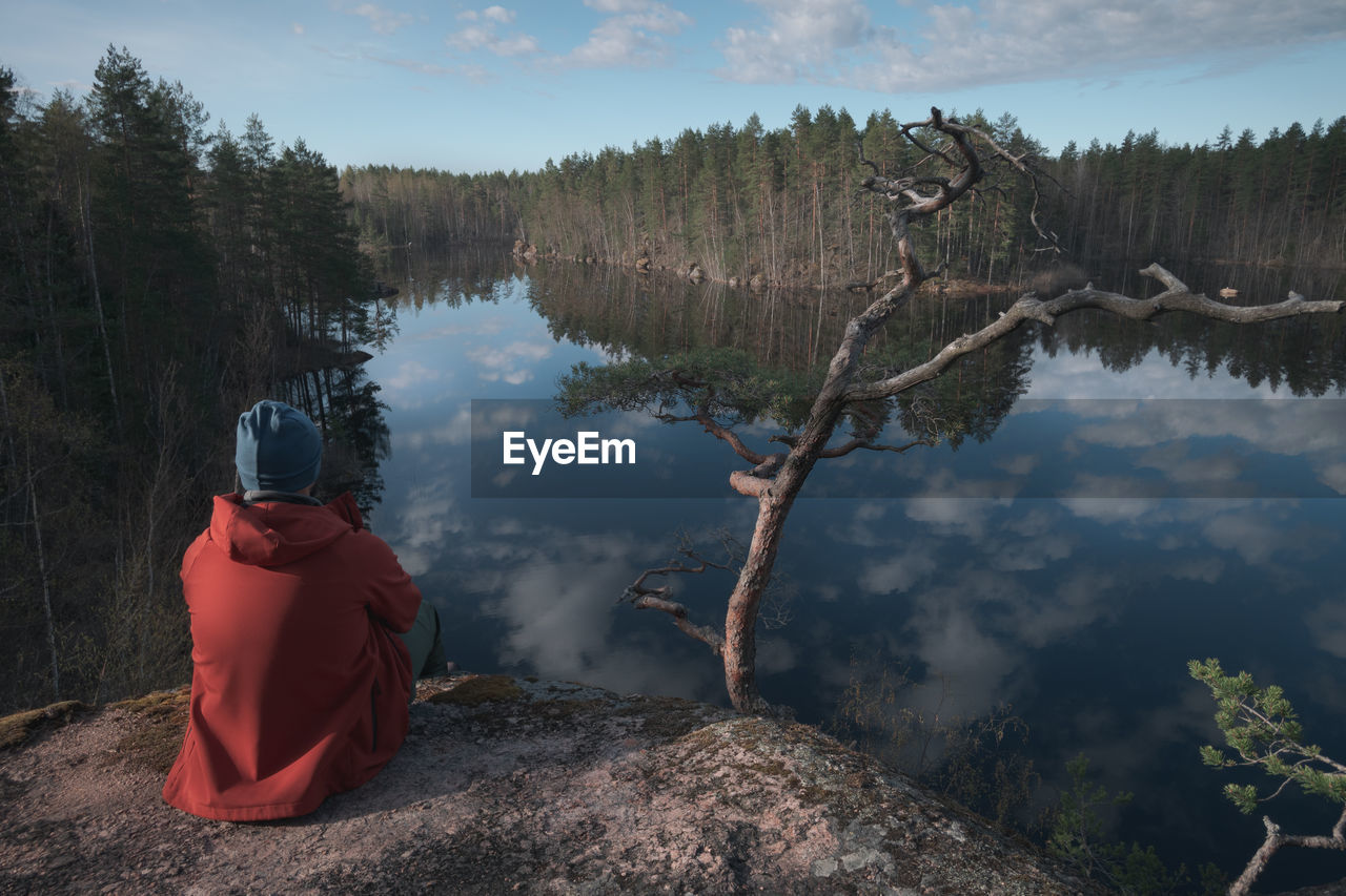 A man is sitting in a beautiful location on the shore of a picturesque forest lake 