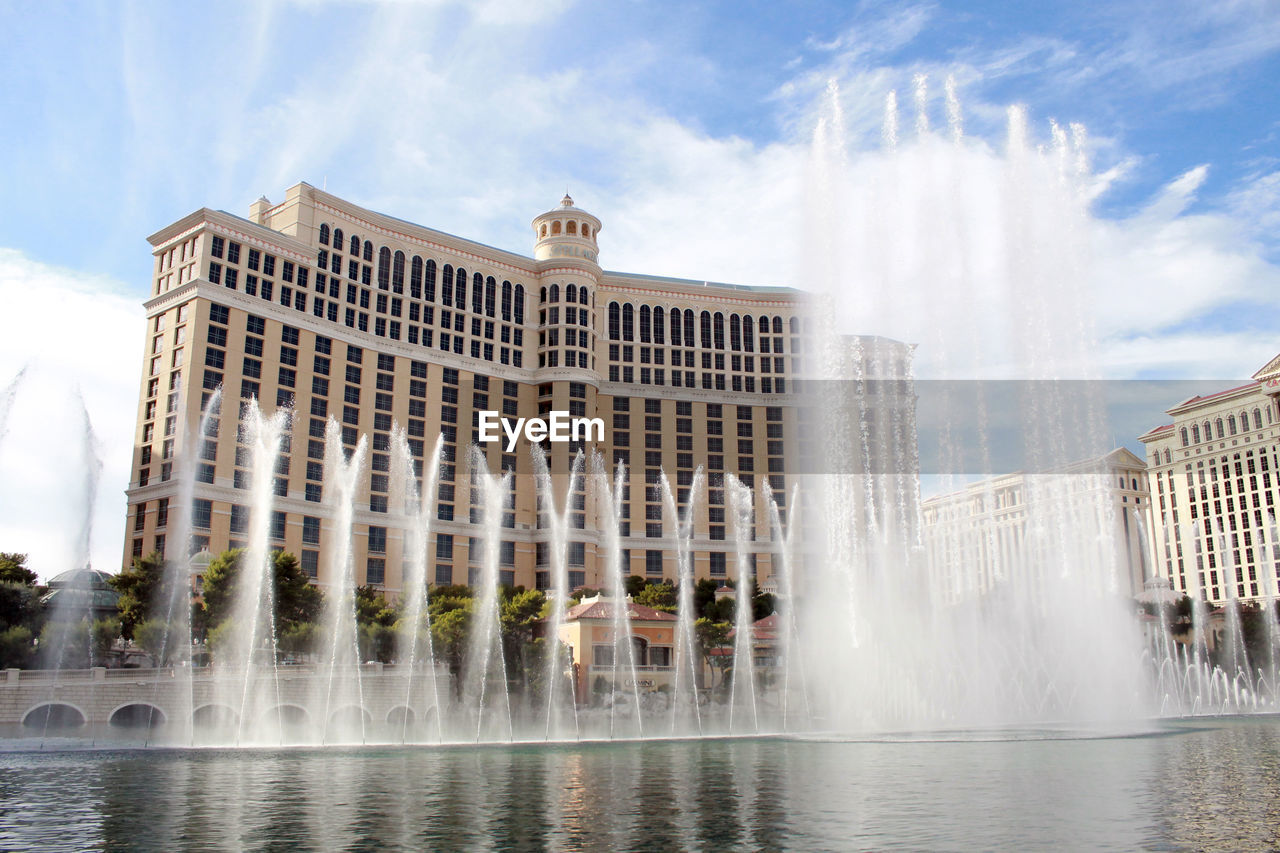 LOW ANGLE VIEW OF FOUNTAIN WITH BUILDINGS IN BACKGROUND