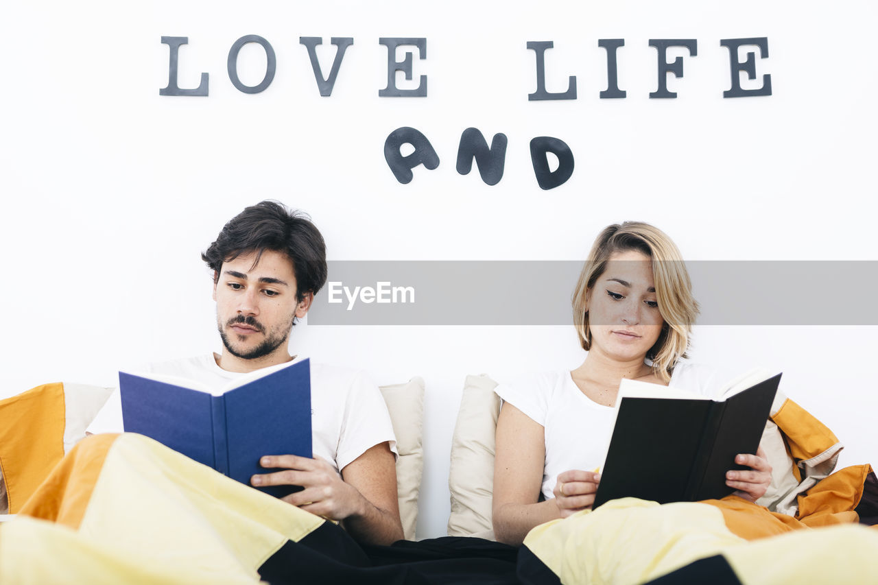 YOUNG COUPLE SITTING ON WALL IN OFFICE