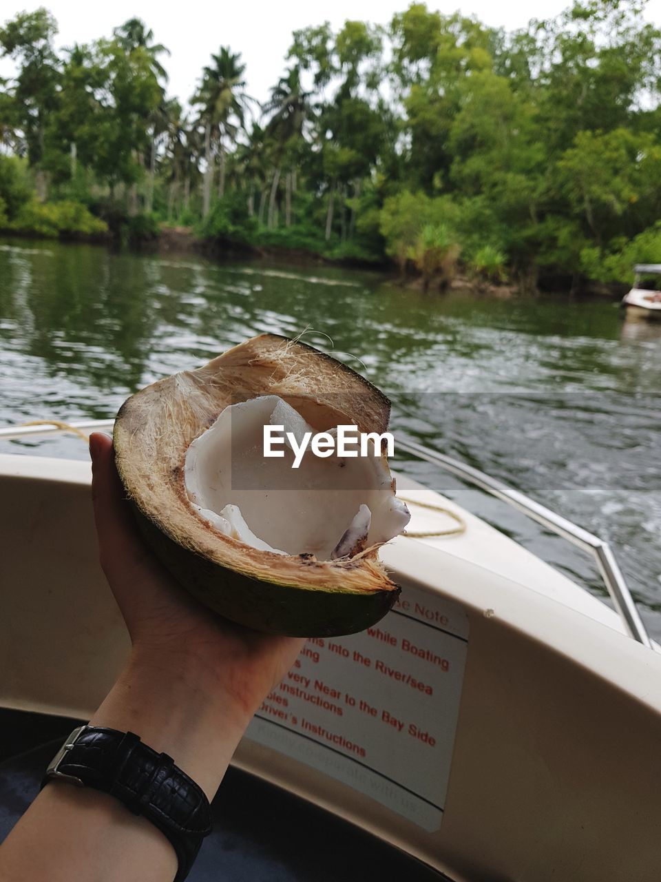 CROPPED IMAGE OF HAND HOLDING ICE CREAM BY LAKE