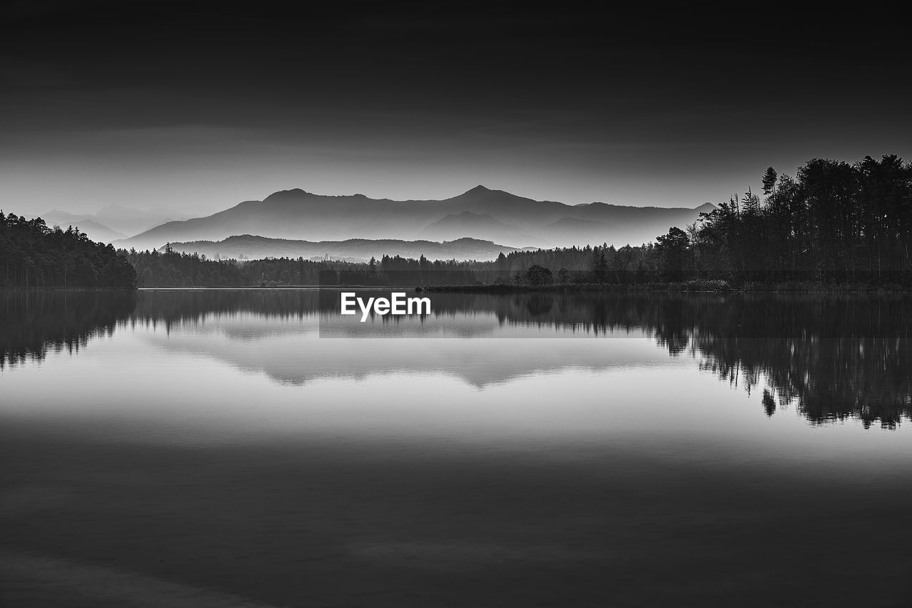 Scenic view of lake by trees against sky