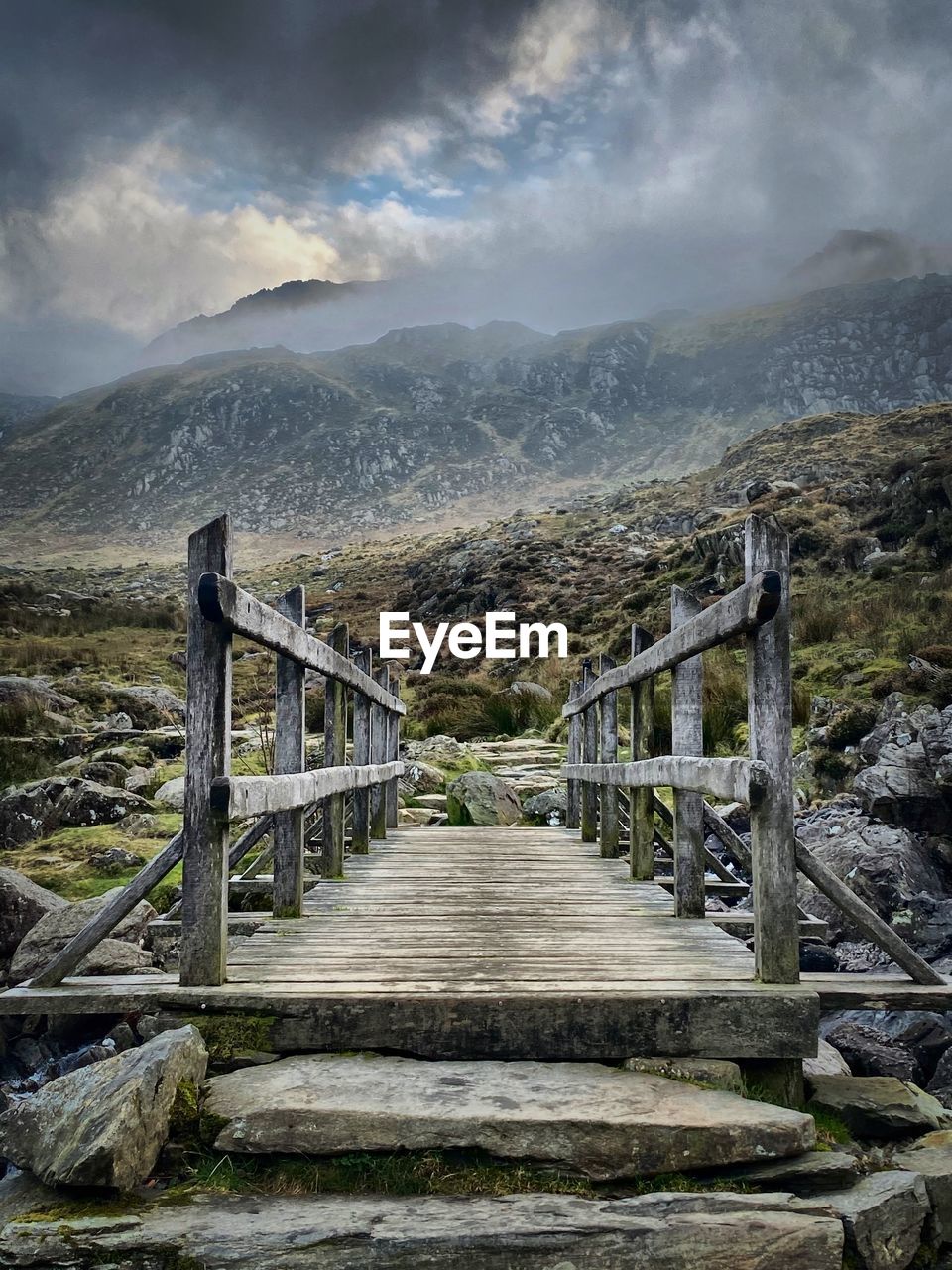 Footbridge over mountains against sky