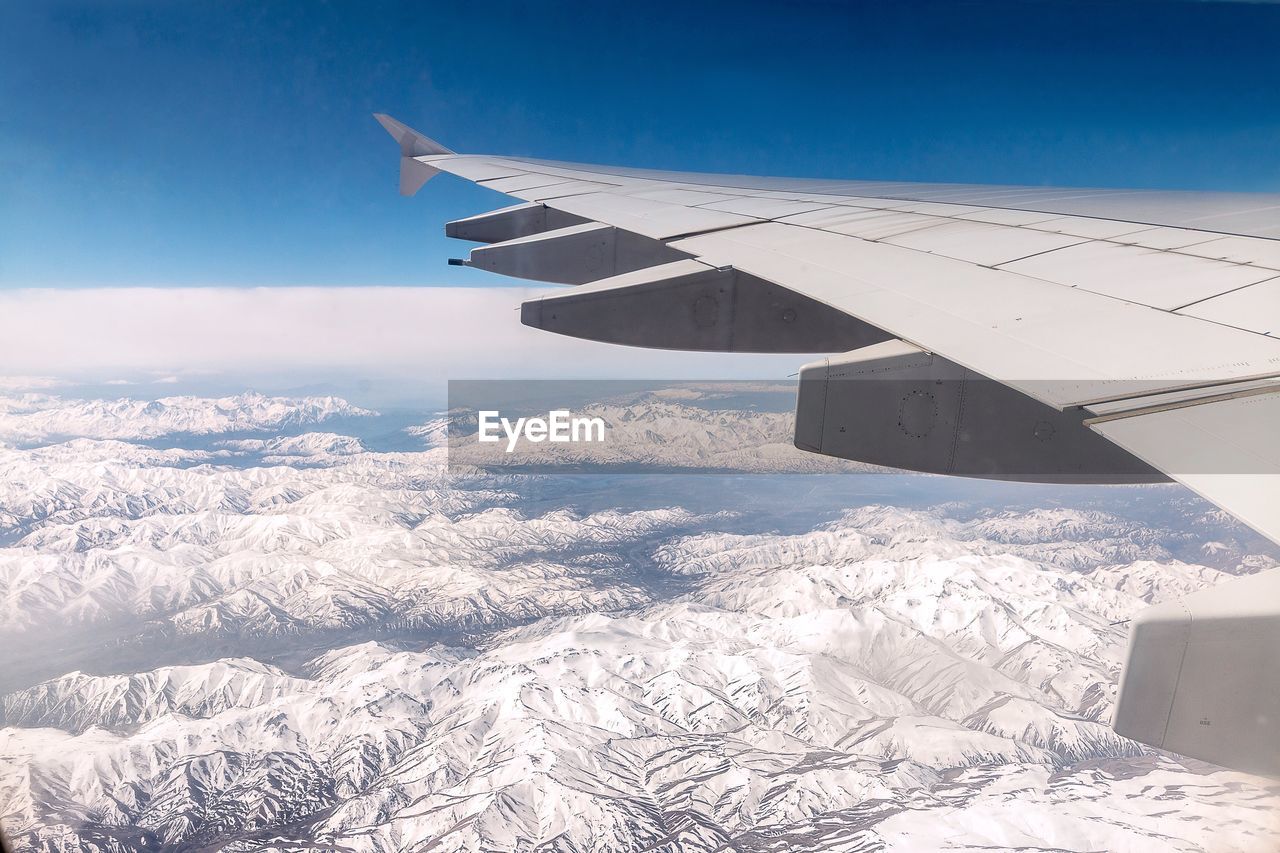 Cropped image of airplane over snowcapped landscape