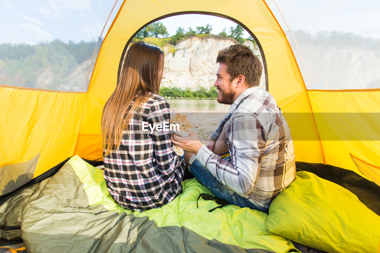 YOUNG COUPLE SITTING ON TENT