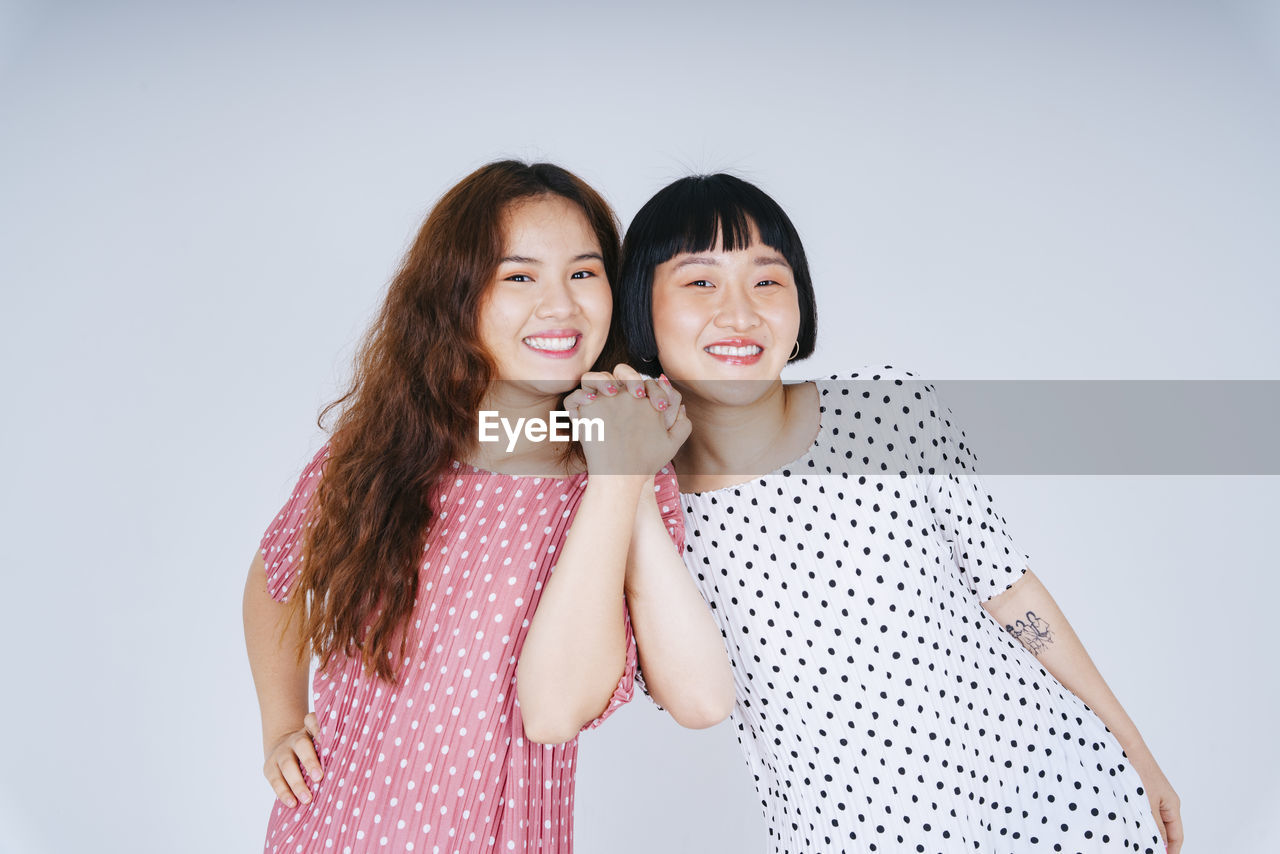 Portrait of happy lesbian couple against gray background