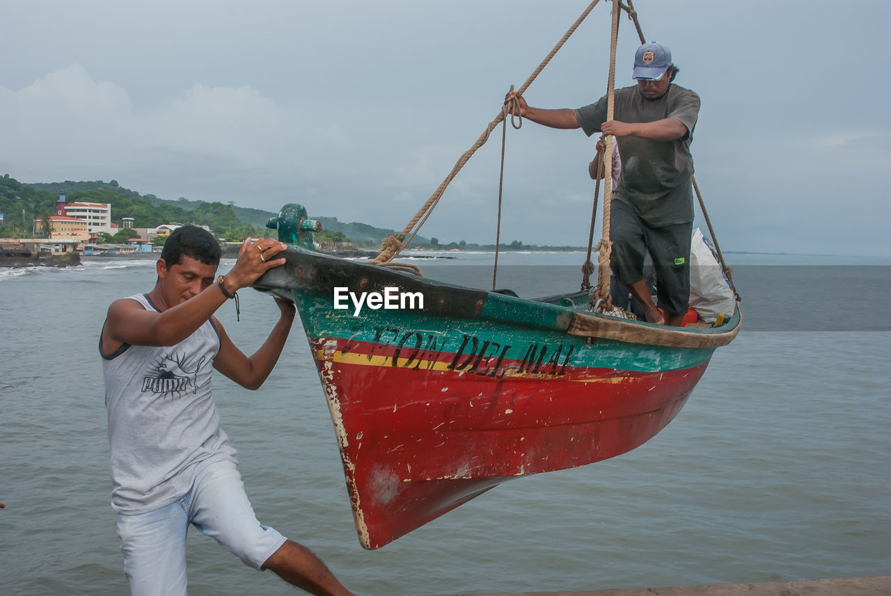 MAN FISHING IN BOAT AGAINST SEA