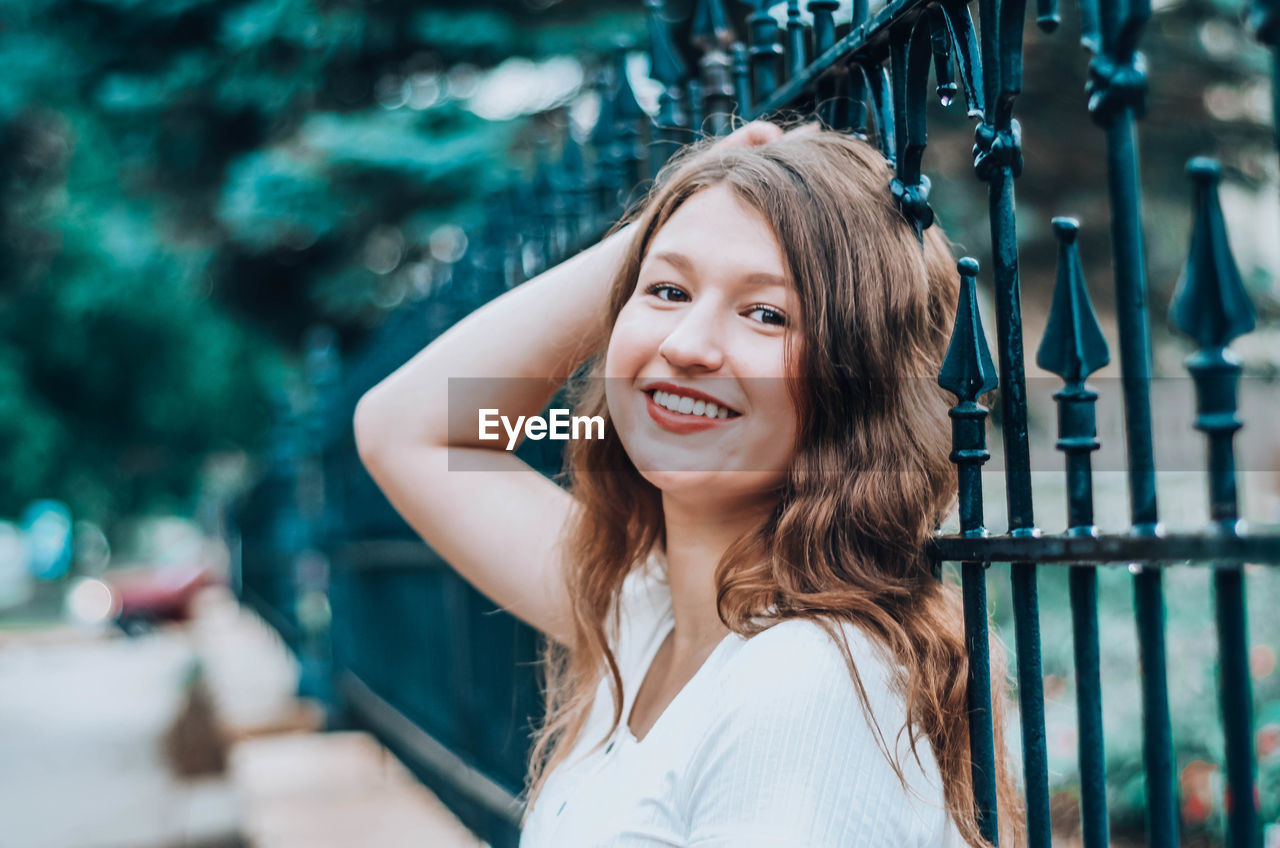 PORTRAIT OF SMILING YOUNG WOMAN OUTDOORS