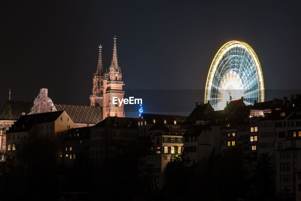 Illuminated wiener riesenrad and church in city against clear sky