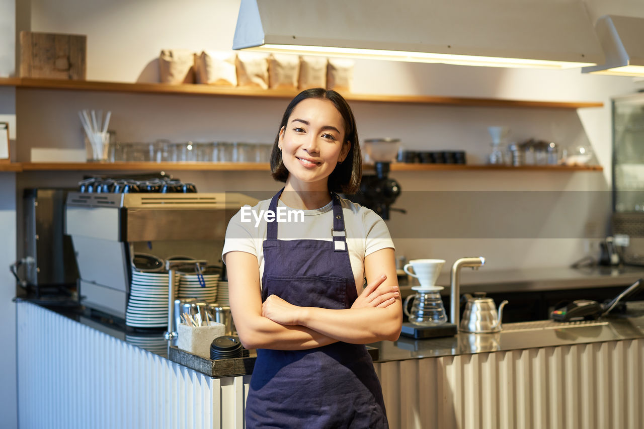 portrait of young woman standing in kitchen at home