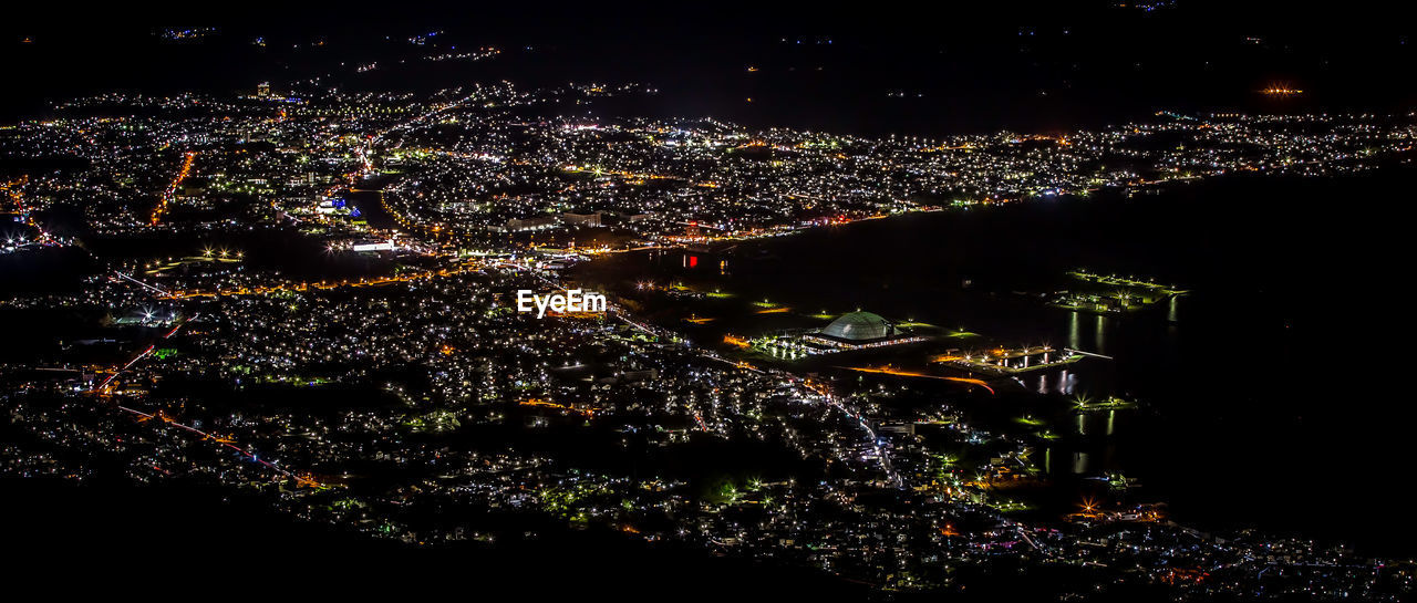 Panoramic view of illuminated city by river at night