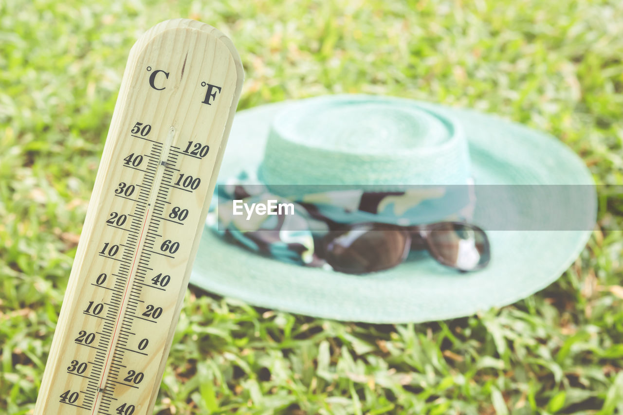 Close-up of thermometer against hat on field