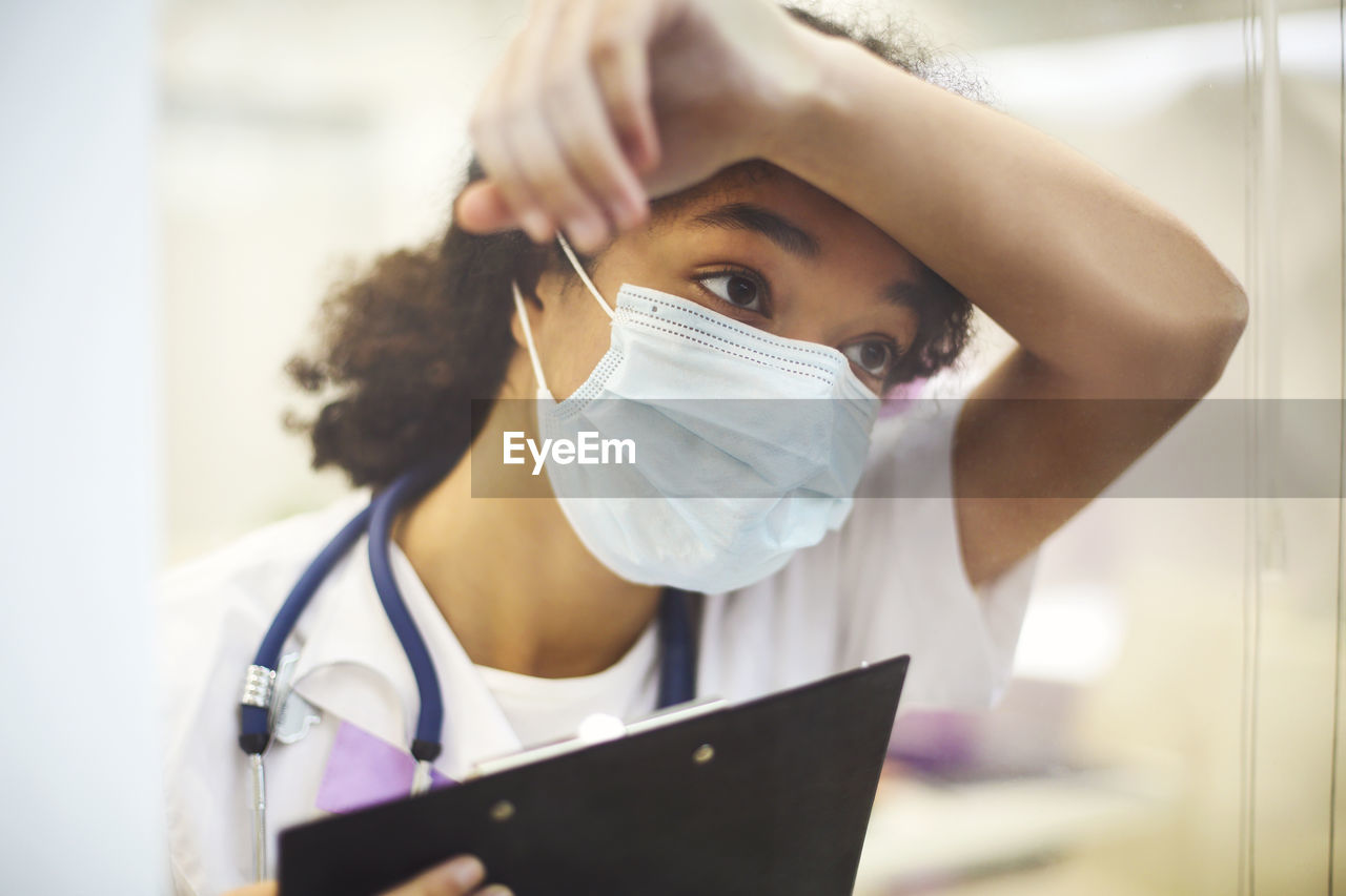 Nurse wearing mask while holding clipboard at clinic