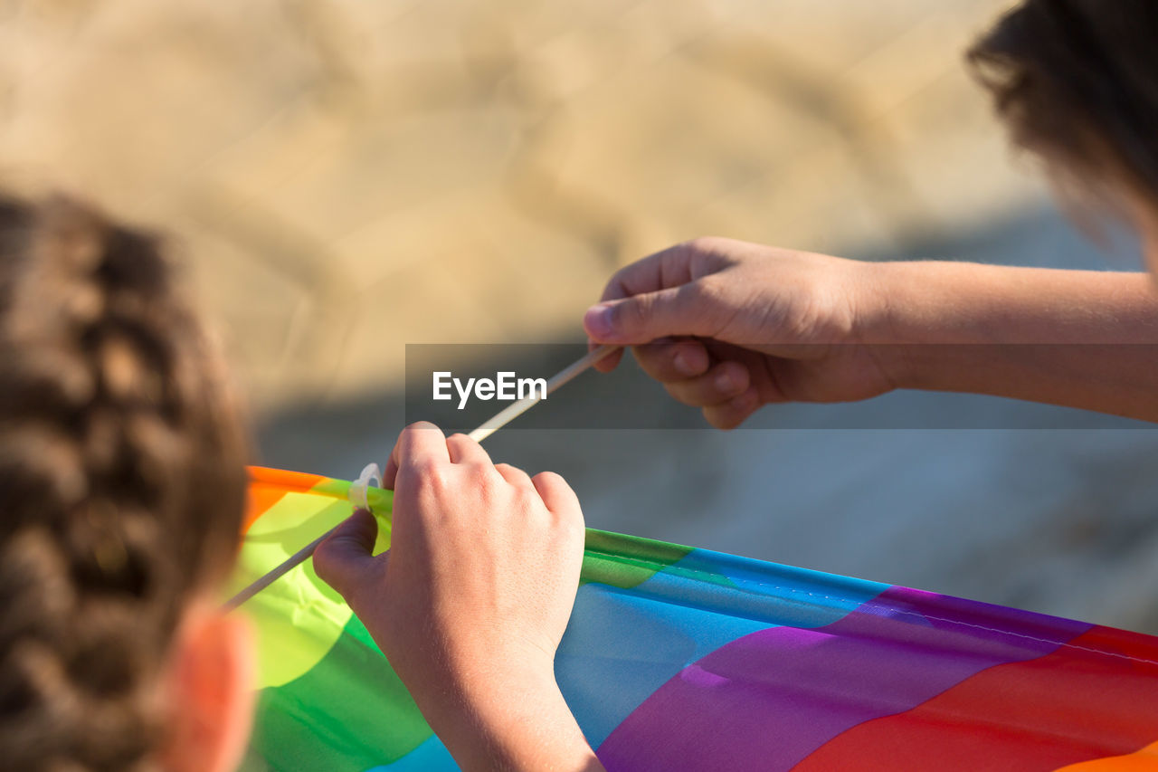 Brother and sister collect kite in nature, close-up.