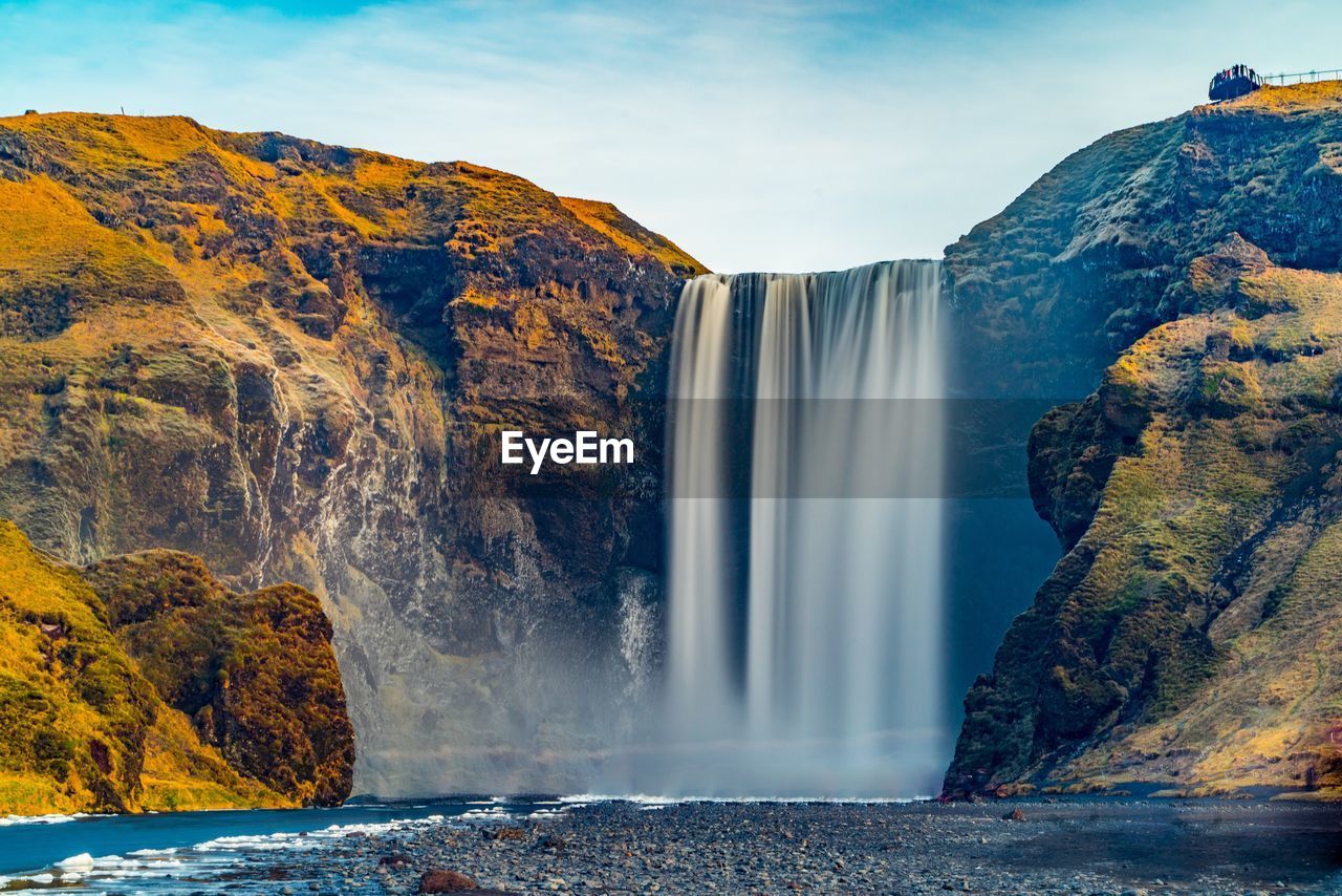 SCENIC VIEW OF WATERFALL AGAINST SKY