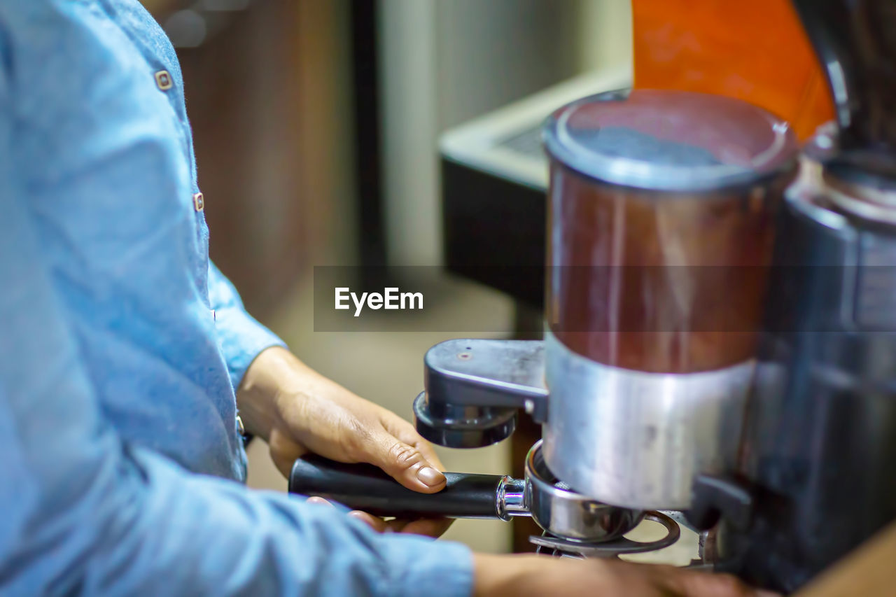 Close up barista is grinding freshly roasted by coffee grinder make beans into a powder.