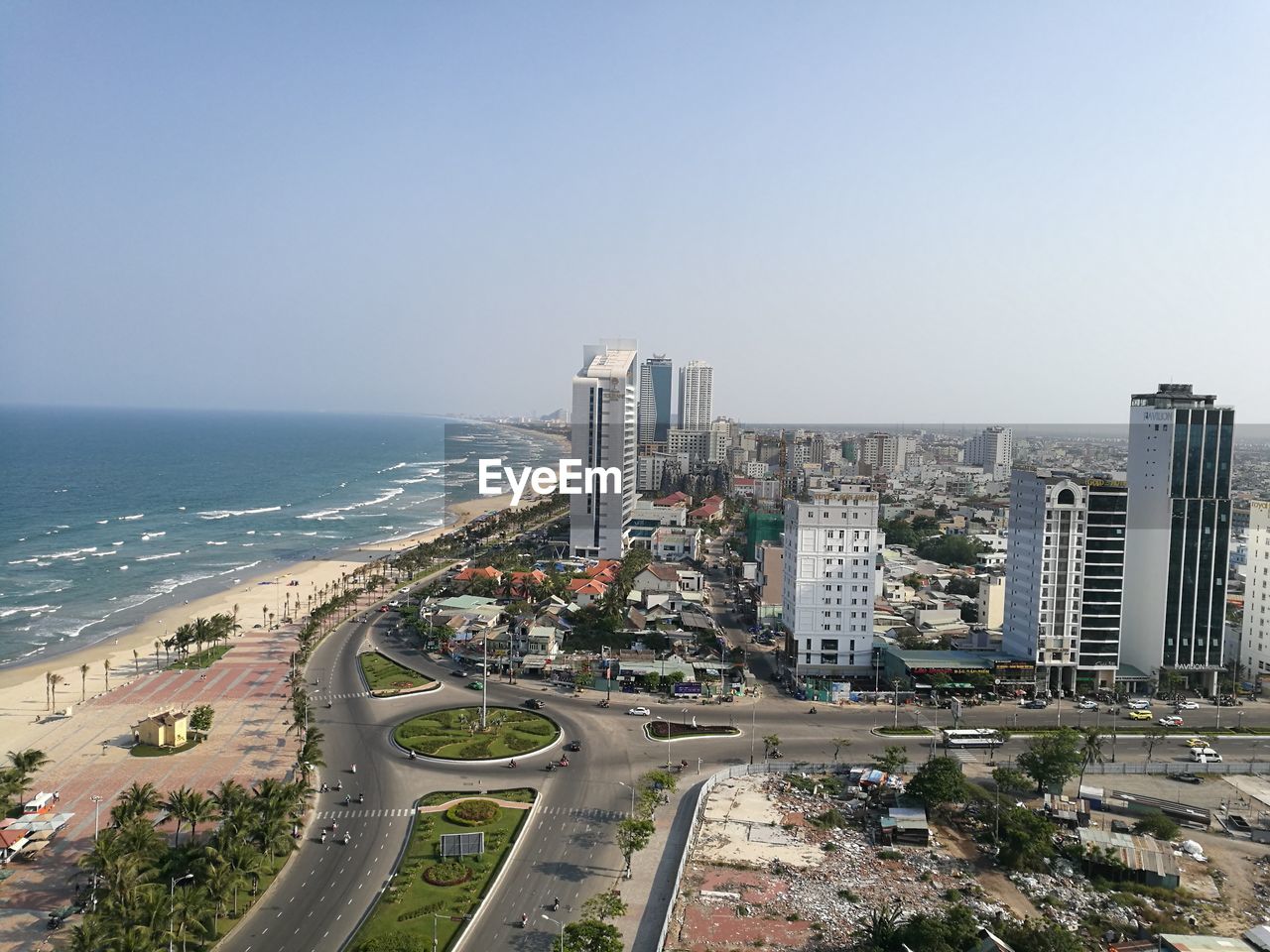 HIGH ANGLE VIEW OF ROAD BY SEA AGAINST BUILDINGS