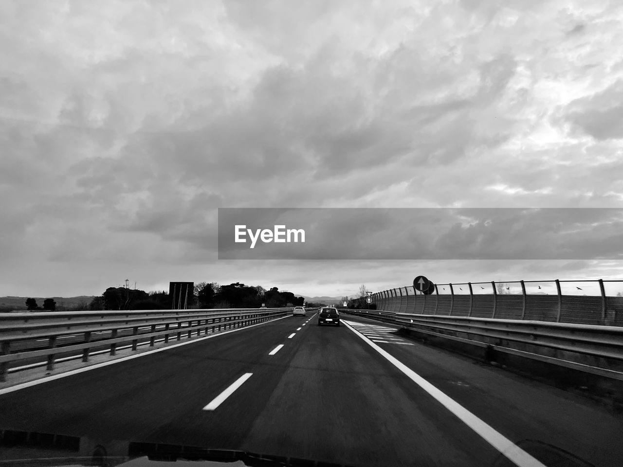 transportation, road, black and white, sky, cloud, monochrome, highway, monochrome photography, mode of transportation, travel, black, car, nature, sign, white, motor vehicle, horizon, symbol, architecture, marking, the way forward, road marking, freeway, no people, city, bridge, outdoors, infrastructure, lane, motion, vanishing point, street, land vehicle, line, built structure, day, on the move, diminishing perspective, multiple lane highway, travel destinations