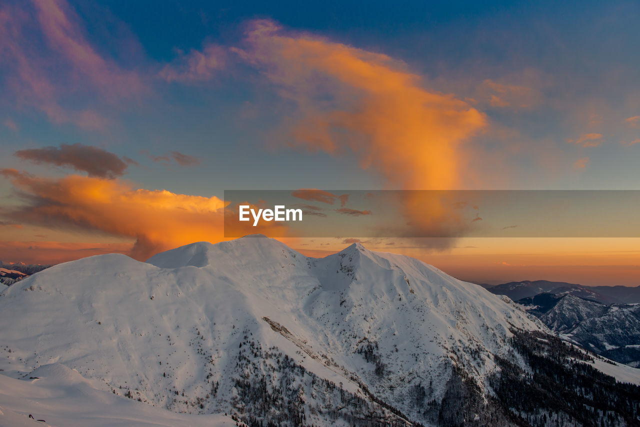 Snowy mountain with clouds at sunset