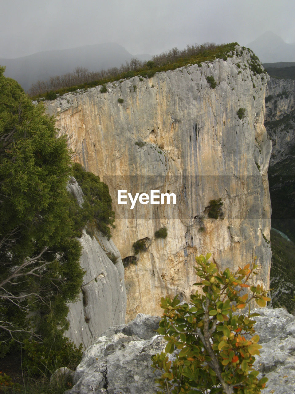 SCENIC VIEW OF CLIFF BY MOUNTAIN AGAINST SKY
