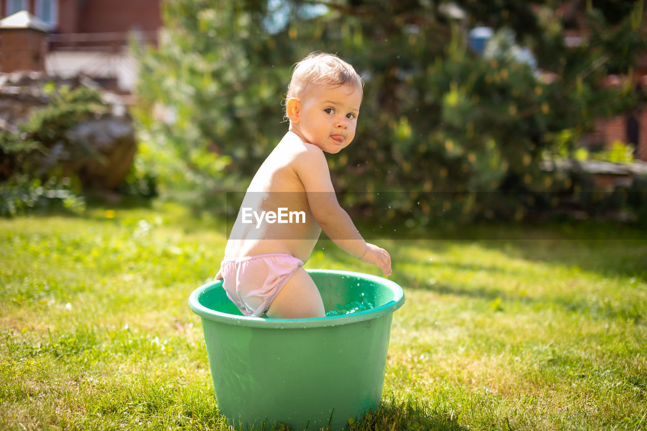 Cute baby girl playing in bucket at lawn