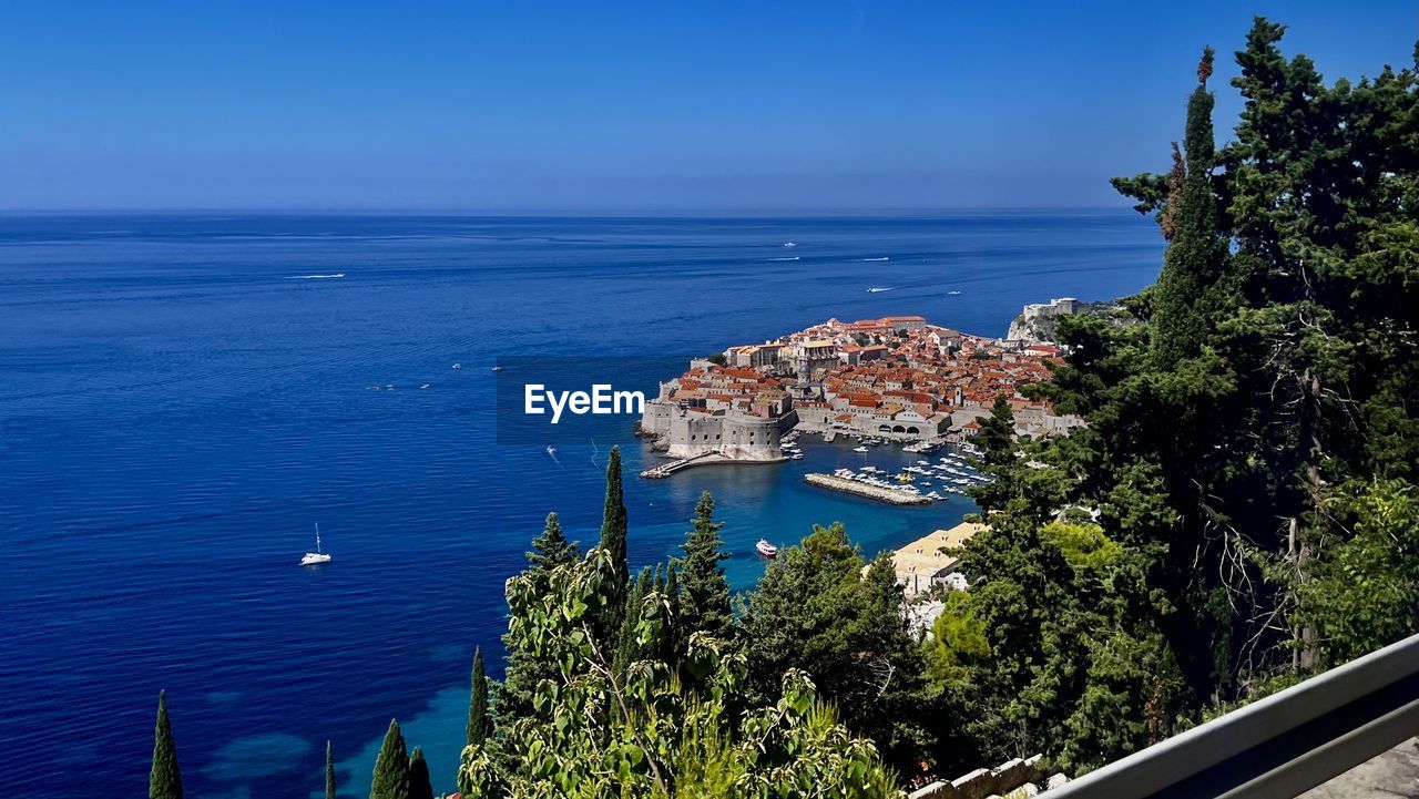 water, sea, vacation, coast, nature, architecture, tree, plant, sky, ocean, built structure, blue, building exterior, no people, high angle view, travel destinations, land, horizon over water, transportation, scenics - nature, travel, bay, beauty in nature, shore, day, nautical vessel, beach, clear sky, outdoors, horizon, building, tourism, city, mode of transportation, tranquility, body of water, sunlight, sunny, tranquil scene