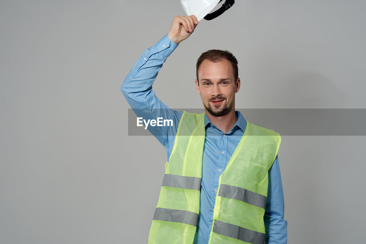 one person, adult, men, studio shot, indoors, person, portrait, waist up, standing, smiling, beard, clothing, facial hair, gray background, gray, business, occupation, happiness, young adult, emotion, front view, holding, hand, dress shirt, human face, copy space, businessman, looking, sleeve, looking at camera, working, tennis, professional occupation, colored background, kitchen utensil