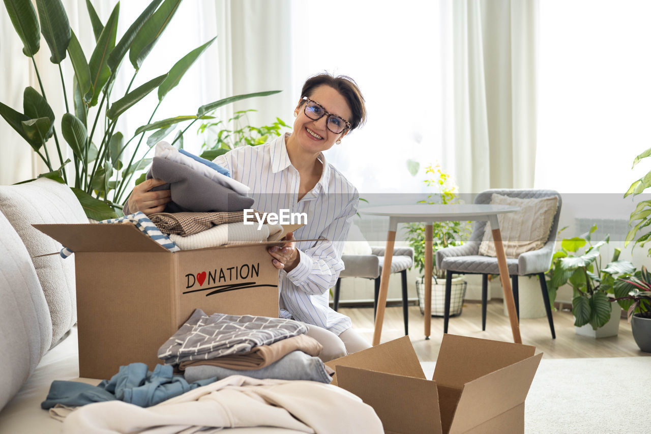 young woman reading book while sitting on sofa at home