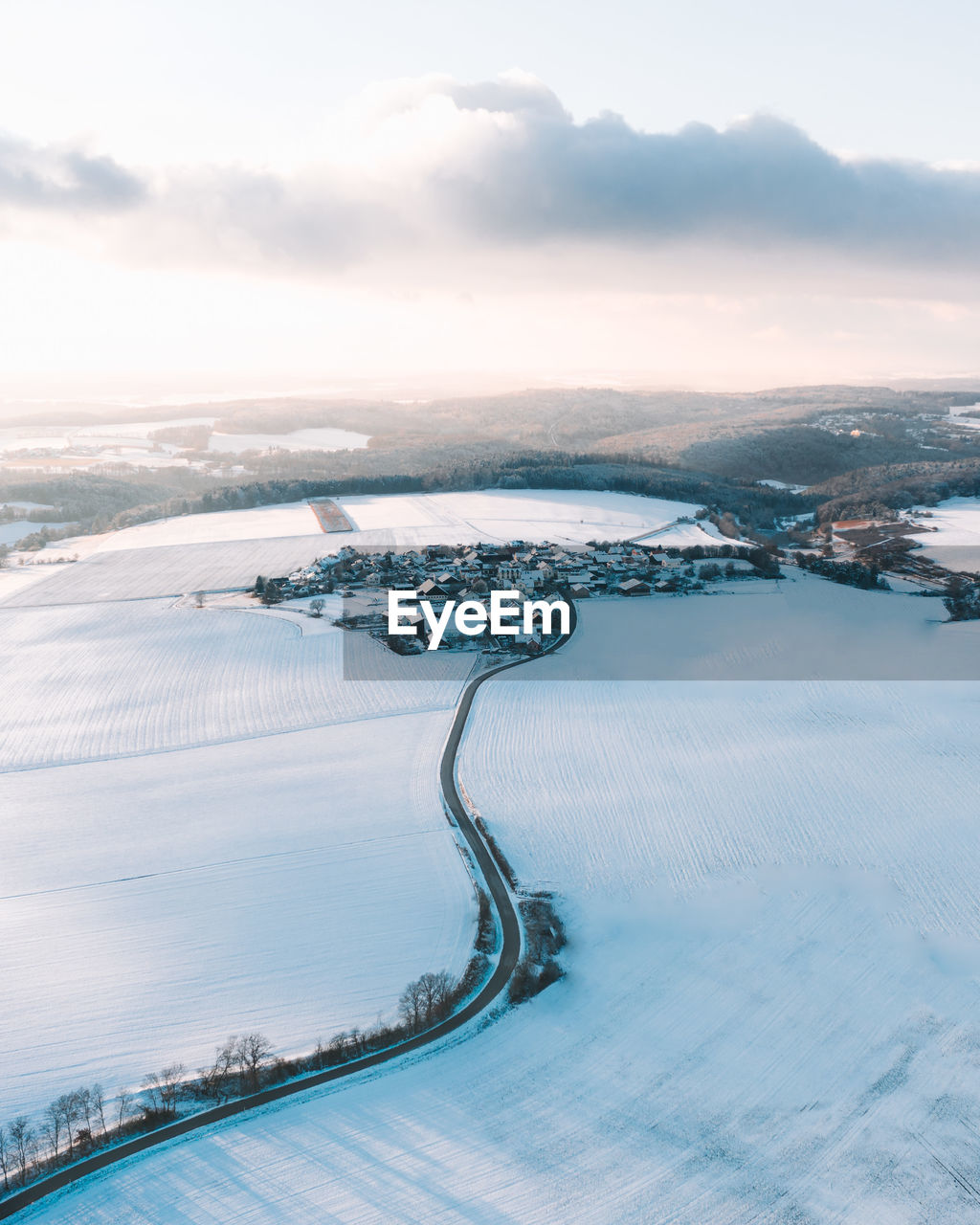 Scenic drone photo of village by snowcapped mountains against sky