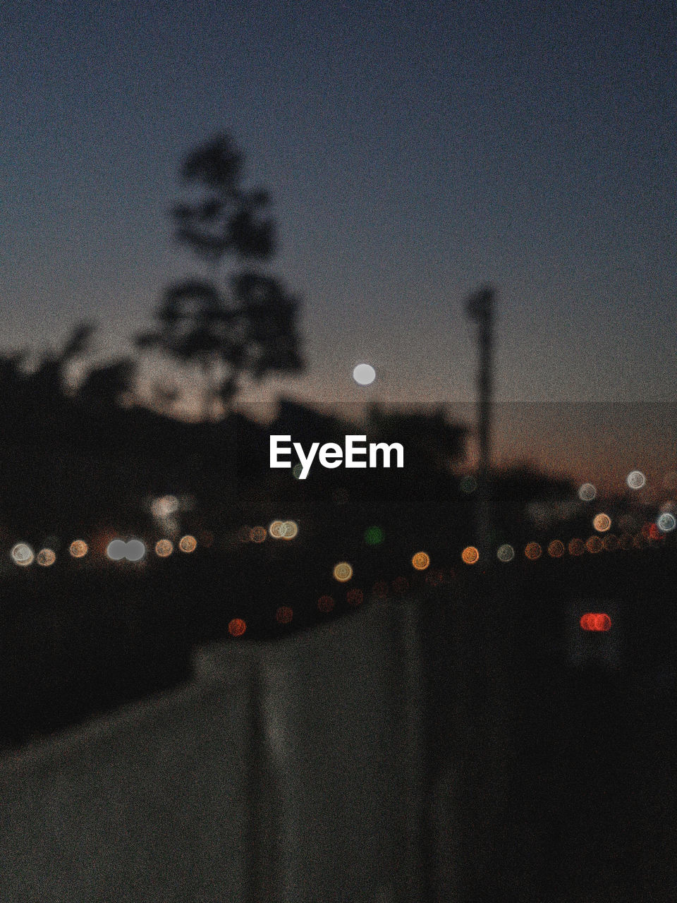 DEFOCUSED IMAGE OF ILLUMINATED CITY AGAINST SKY AT DUSK