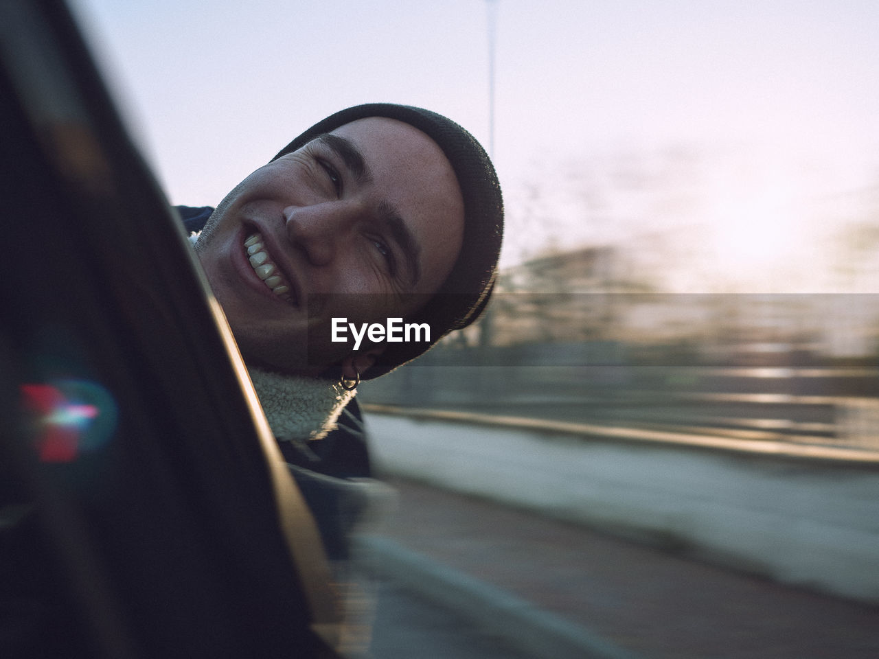 Close-up of smiling man in car against sky