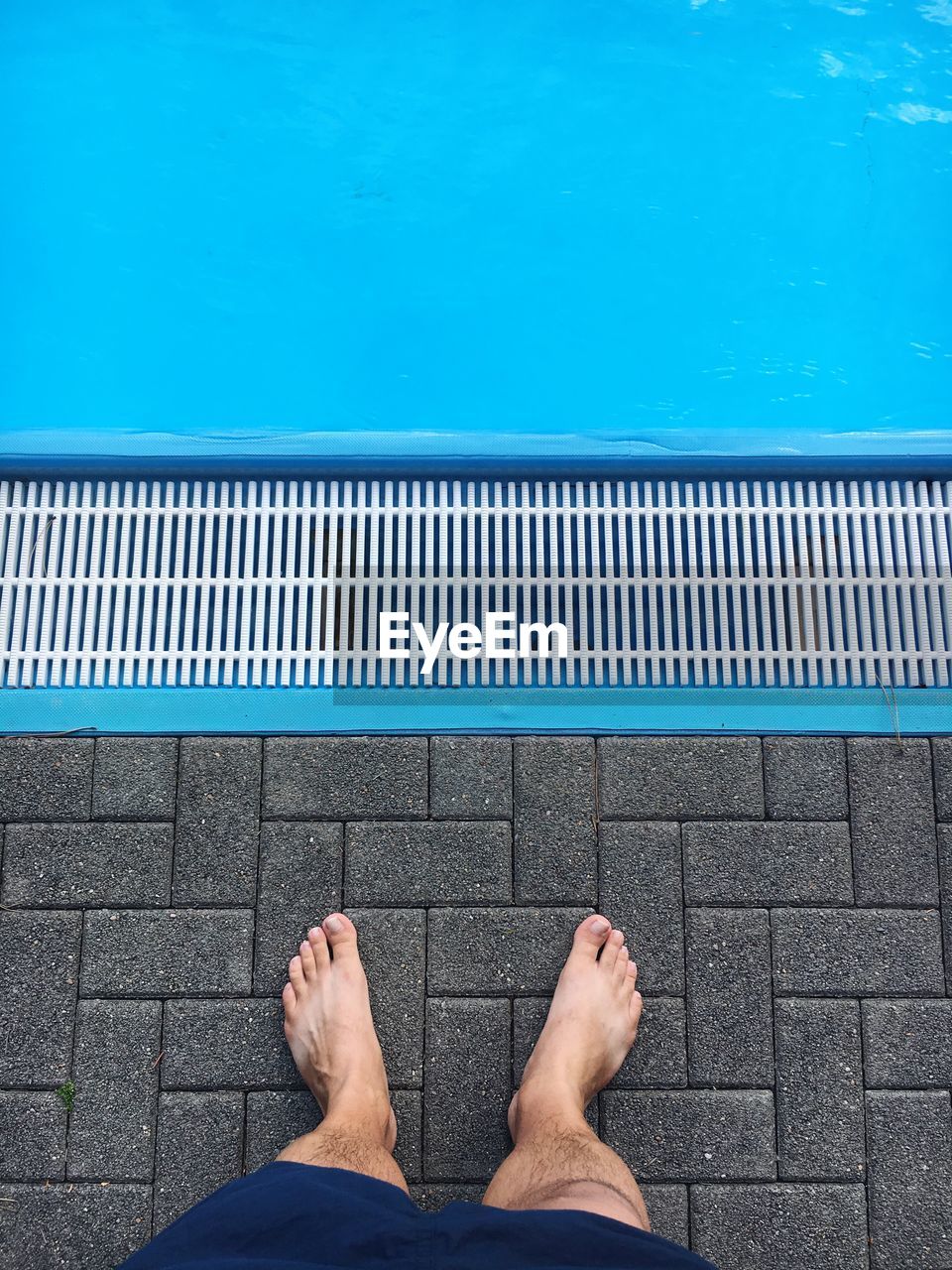 Low section of man standing at poolside