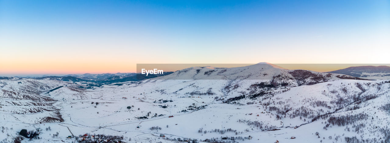 Scenic view of snow covered mountains against sky during sunset