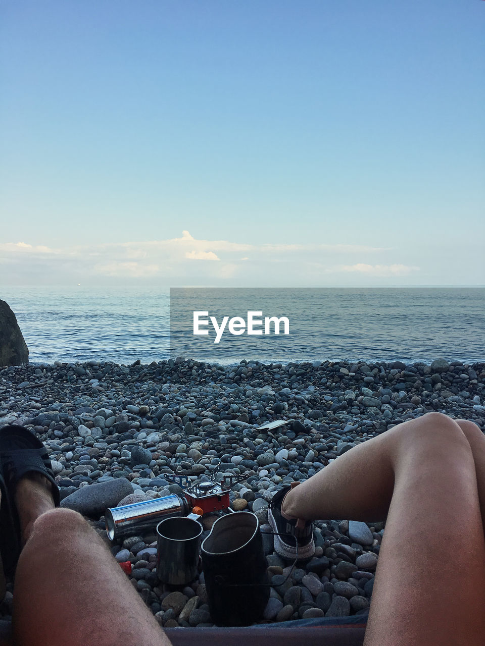 LOW SECTION OF PEOPLE RELAXING ON SHORE AT BEACH