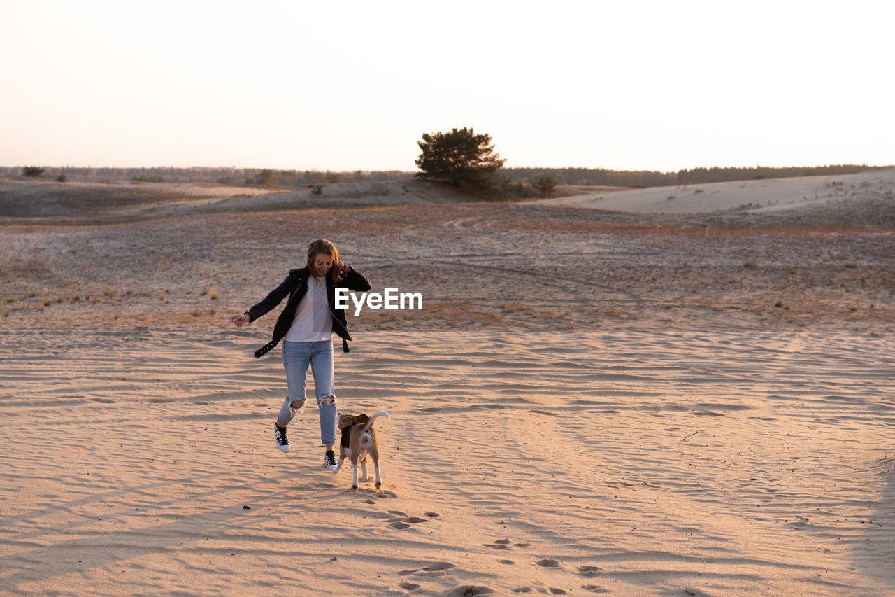 Rear view of woman walking on beach against clear sky